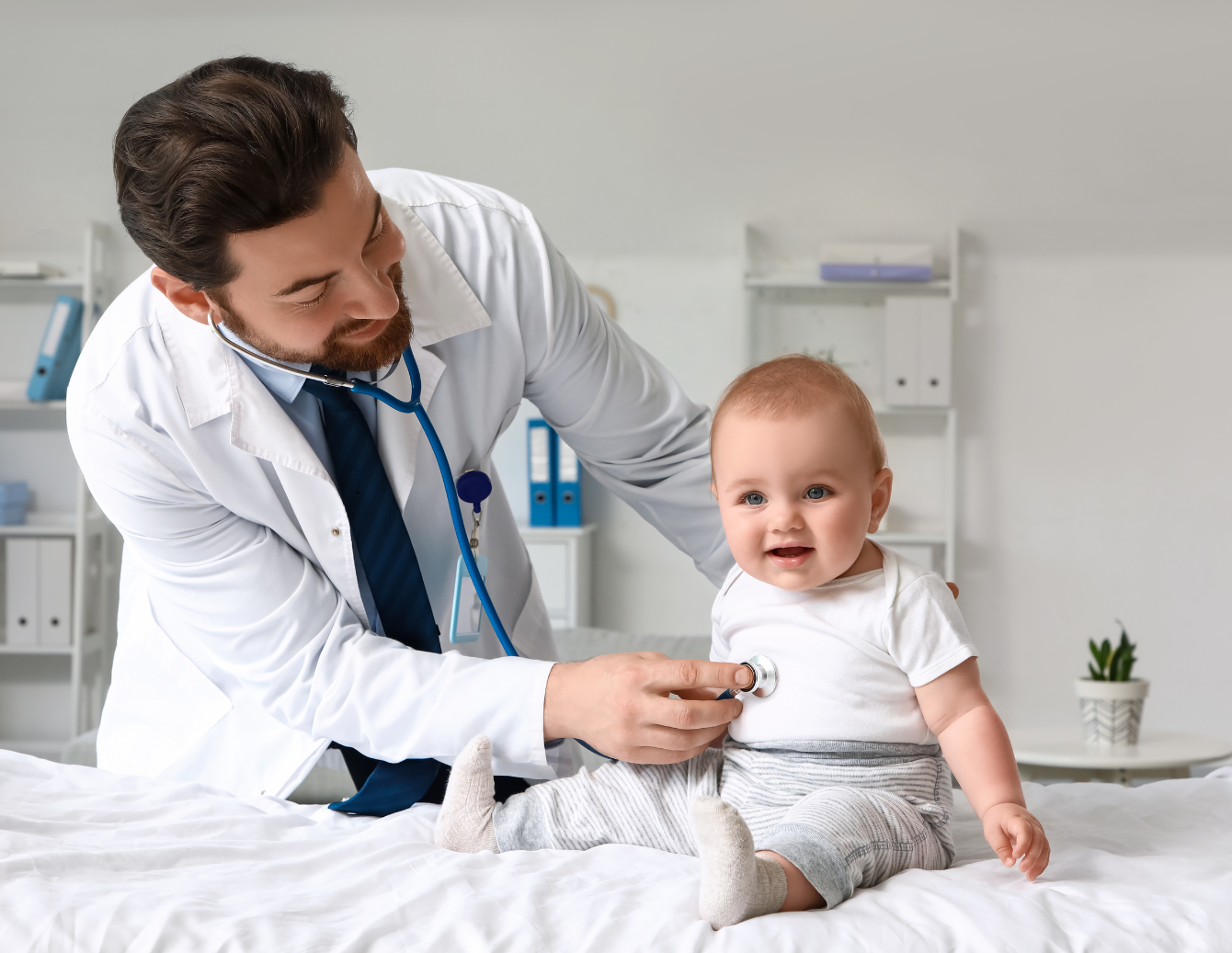 A pediatric clinician uses a stethoscope to listen to a smiling infant’s heartbeat during a medical exam, highlighting the importance of early detection and care for congenital heart defects.